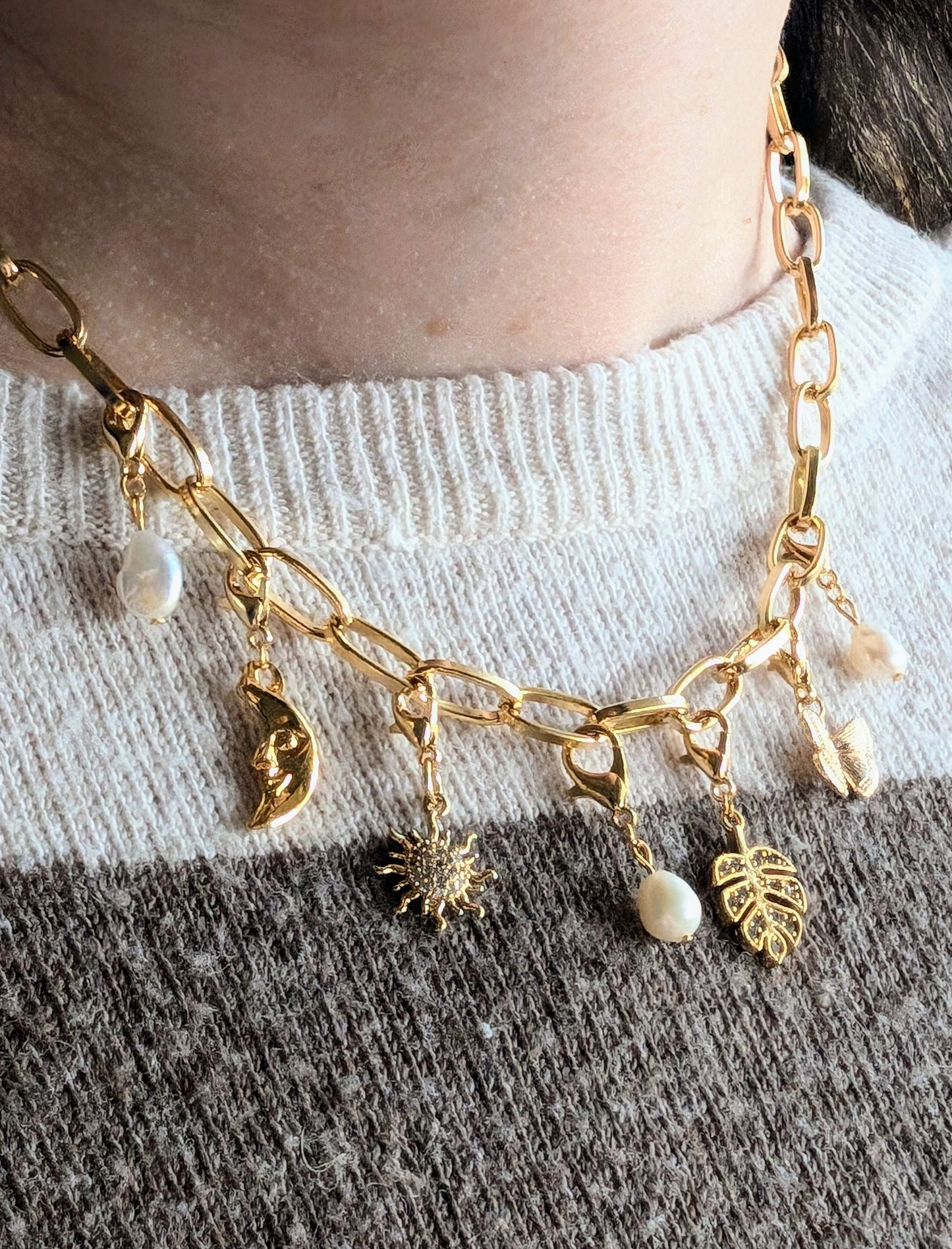 Model wearing the 24k gold oval paperclip chain necklace layered with other gold jewelry.