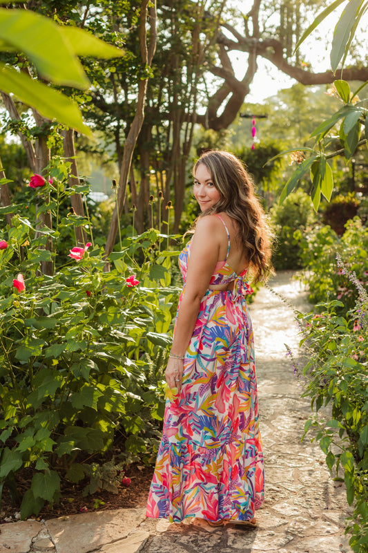 Ashley, founder of Charlotte’s Cove, wearing layered coastal jewelry in a colorful tropical setting.