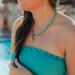 Woman wearing a turquoise dress and necklace by a pool wearing the turquoise marina earrings. 