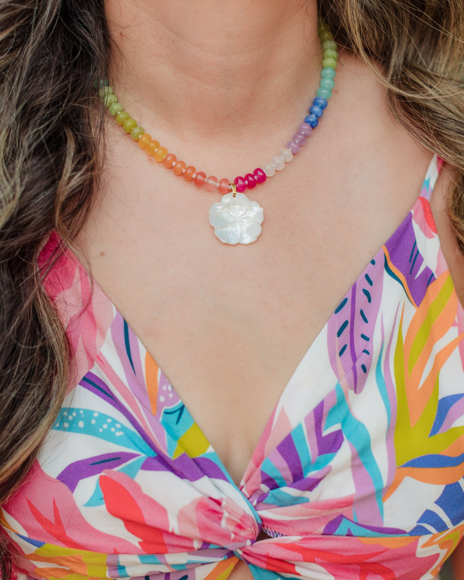 Woman wearing the Aloha Rainbow colorful gemstone and mother-of-pearl hibiscus necklace