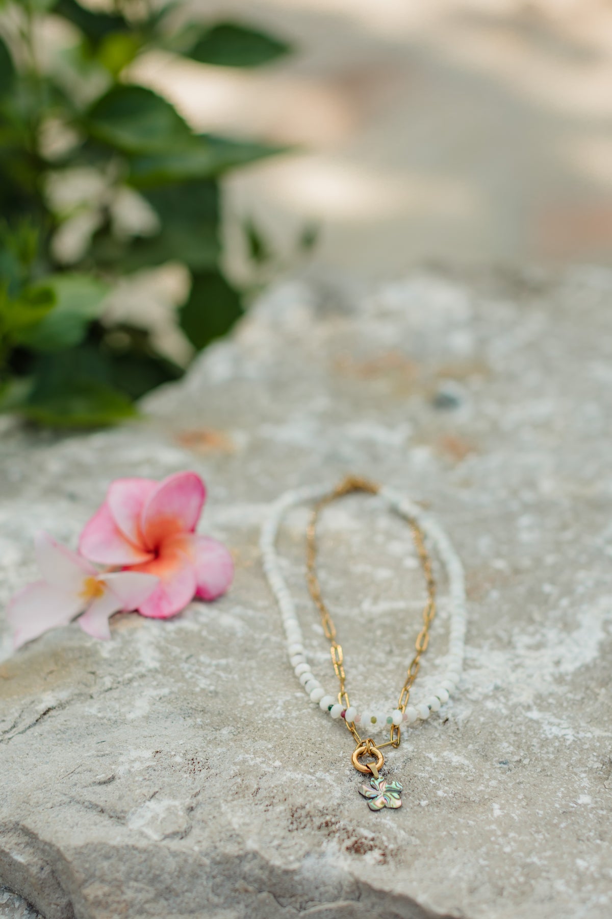 Necklace with a pink flower on a stone surface