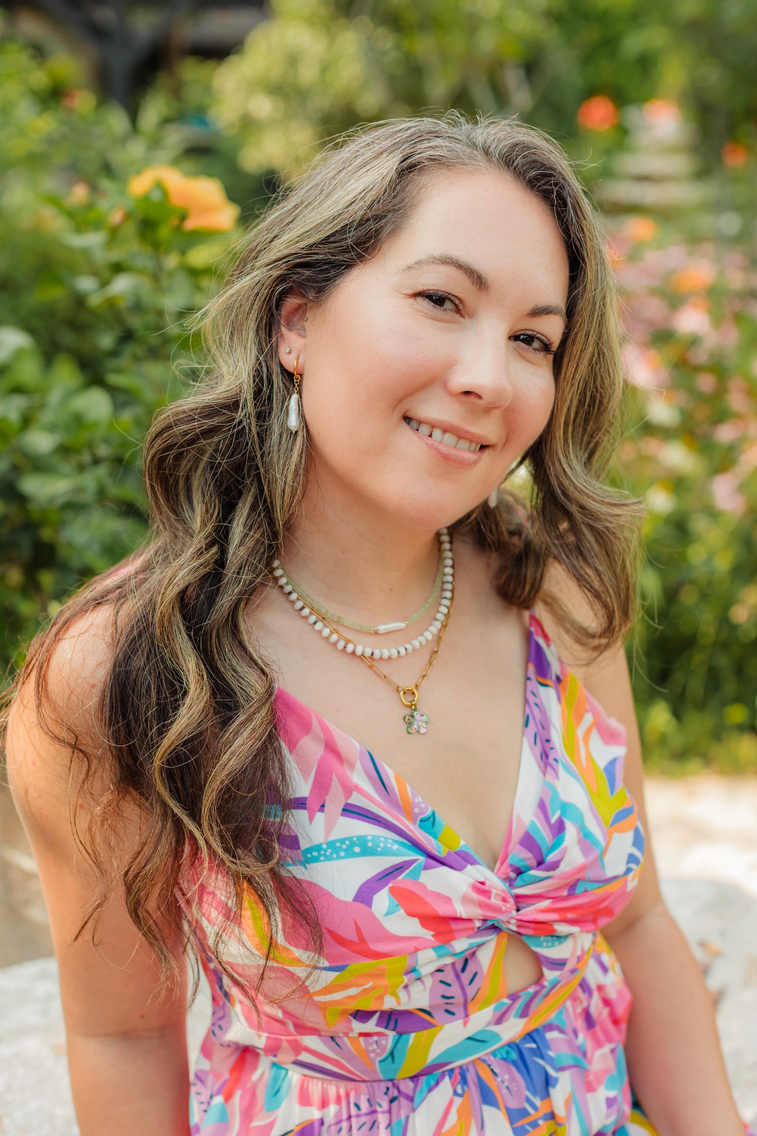 Woman in a colorful dress sitting outdoors with greenery in the background