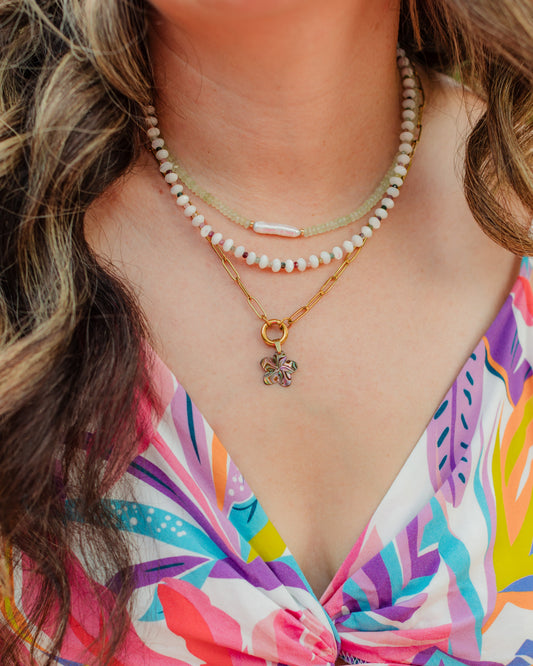 Woman wearing the Maui Bloom abalone shell flower necklace in a colorful layered coastal jewelry look