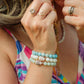 Close-up of a person wearing colorful bracelets and rings with a multicolored top.
