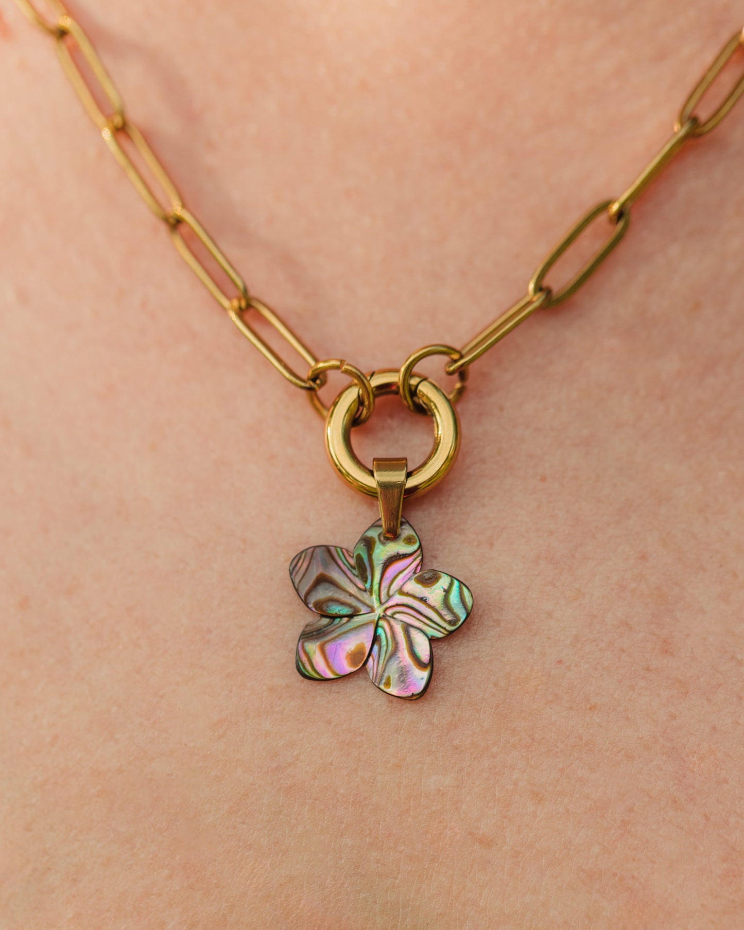 Gold necklace with a colorful flower pendant on a person's neck