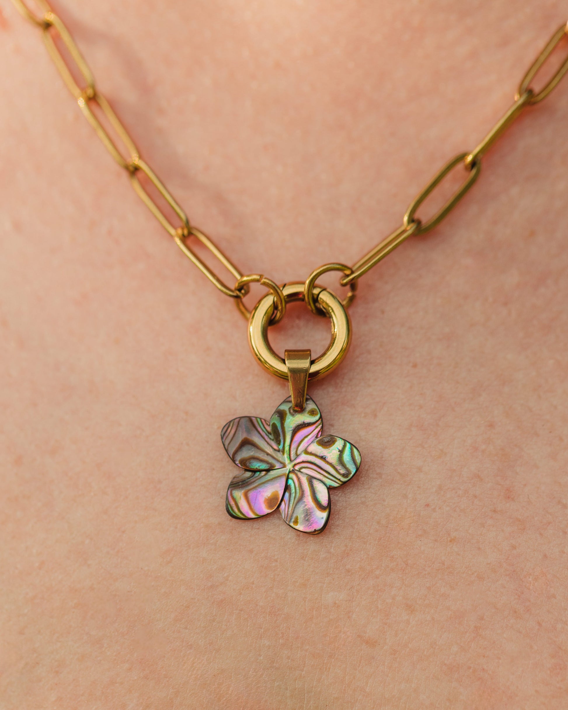 Gold necklace with a colorful flower pendant on a person's neck