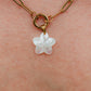 Gold chain necklace with a white flower pendant on skin
