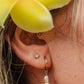 Close-up of an ear with pearl earrings and a yellow flower in hair