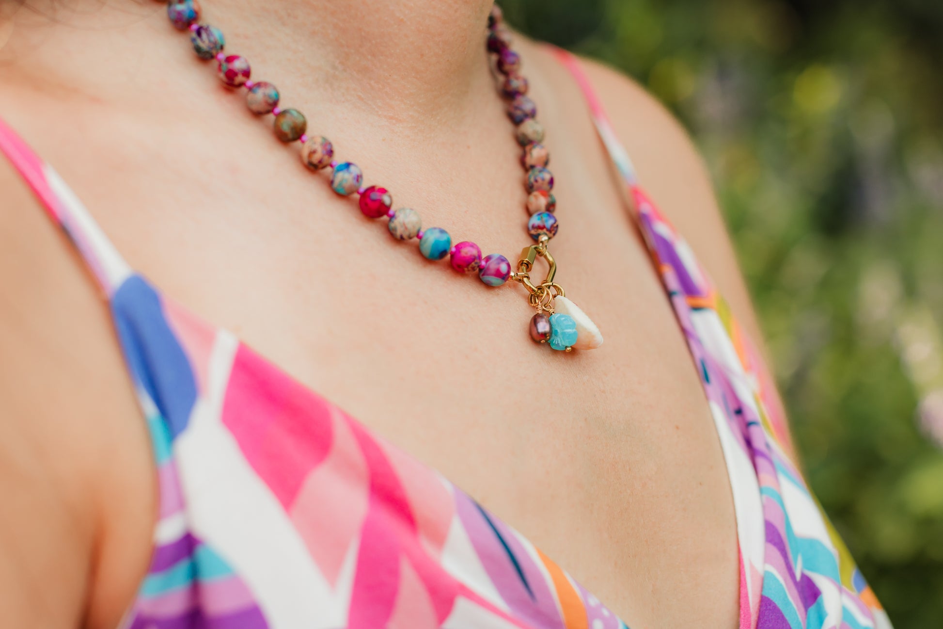 Hand-strung sea sediment jasper gemstone necklace featuring marbled berry, turquoise, and sandy neutral tones with a gold carabiner clasp and removable coastal-inspired charms.
