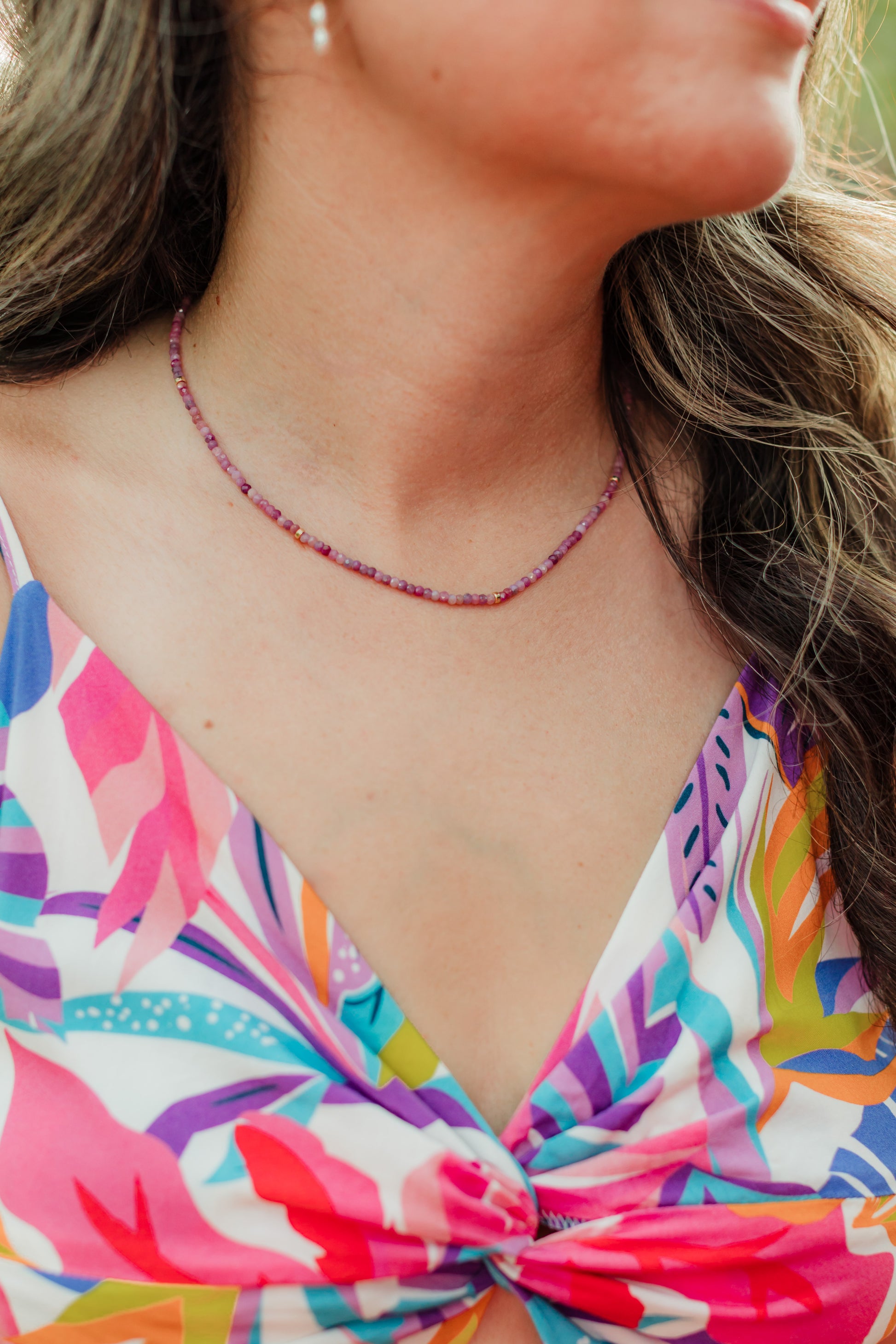 Hand-strung genuine faceted pink ruby gemstone necklace with 18K Gold PVD accents, inspired by the soft pink and purple colors of Hawaiian sunsets.