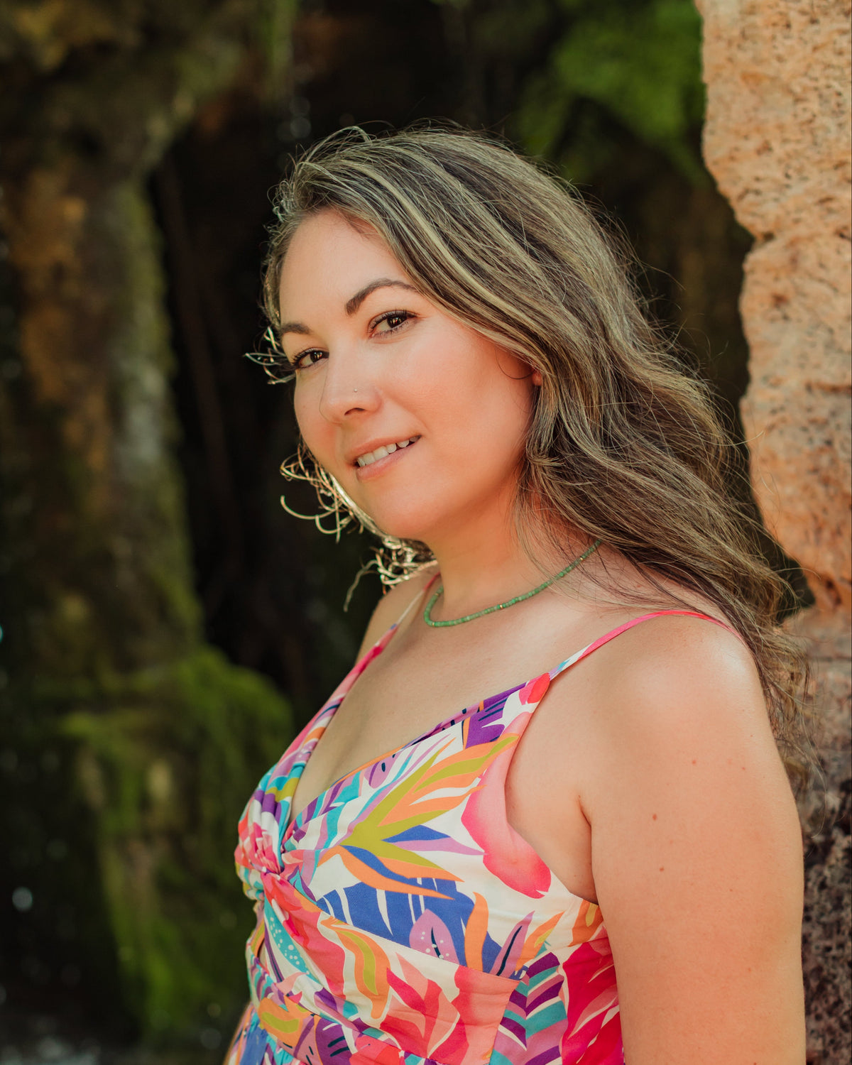 Woman in a colorful dress standing in front of a natural background