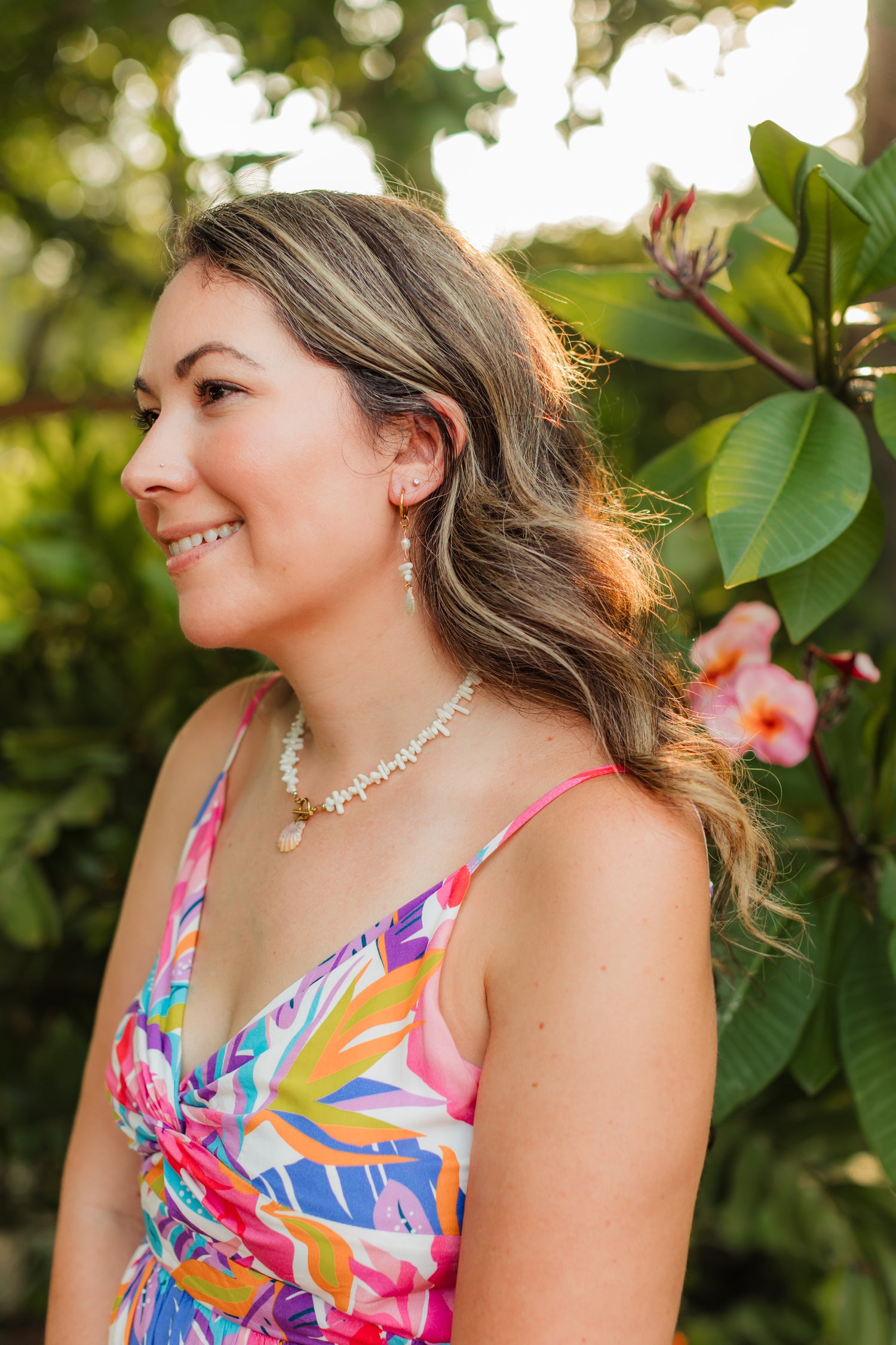 Woman in a colorful dress standing outdoors with greenery and flowers in the background