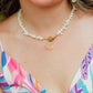 Woman wearing a colorful dress with a blurred green background wearing Hawaiian sunrise shell necklace 