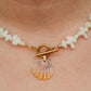 Hand-strung necklace featuring genuine coral chips, freshwater pearl accents, an authentic Hawaiian sunrise shell pendant, and an 18K Gold PVD toggle clasp inspired by the colors of Hawaiian sunrises.
