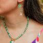 Hand-strung Peruvian turquoise gemstone necklace featuring an 18K Gold PVD oval carabiner clasp with removable charms including a turquoise Swarovski crystal, Czech glass hibiscus, Hawaiian spotted drupe shell, and freshwater pearl.