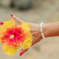 Lavender Bloom Bracelet featuring genuine polished white shell beads, a rare natural lavender cone shell centerpiece, and 14K gold-filled accent beads inspired by Hawaii's hidden beach treasures.