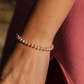 Close-up of a hand wearing a pearl bracelet with a blurred background