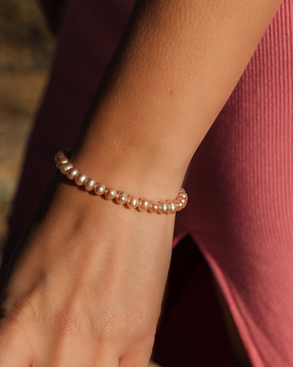 Close-up of a hand wearing a pearl bracelet with a blurred background