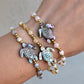 Close-up of an Abalone Sea Turtle Bracelet featuring a carved abalone shell turtle, mother of pearl accents, and 18K gold-filled beads, strung on a stretch cord.