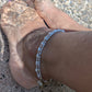 Layered pearl anklet styled with gold jewelry for a coastal summer look