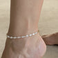 Woman wearing a dainty freshwater pearl anklet with gold accents for coastal everyday style