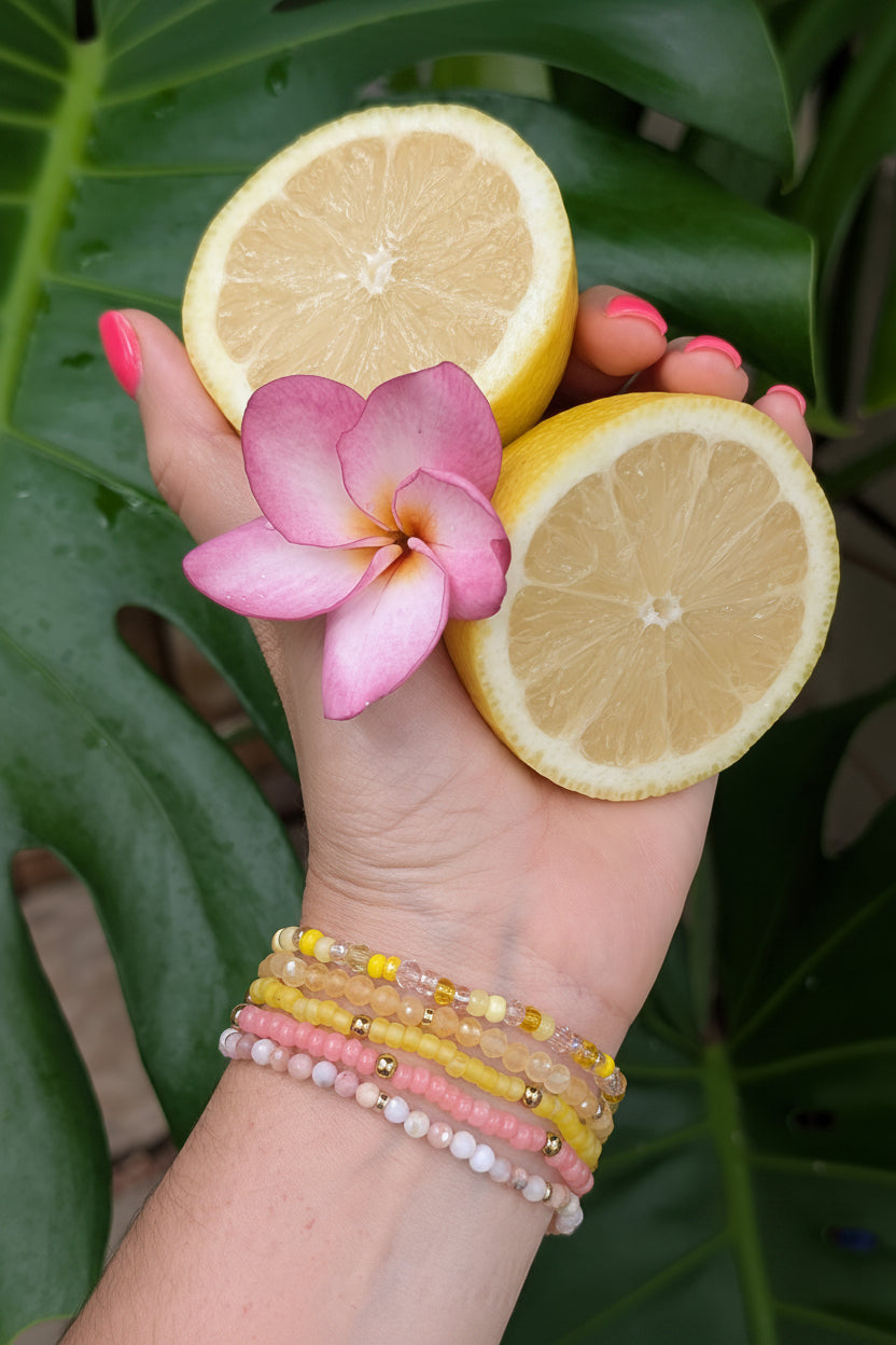 Woman wearing a pink and yellow summer bracelet stack inspired by pool days and lemonade