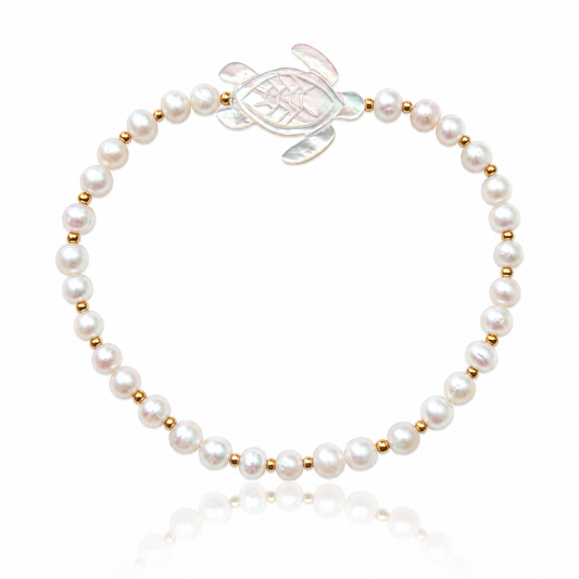Honu Pearl Bracelet featuring genuine round freshwater pearls, polished 18K gold PVD spacer beads, and a hand-carved mother of pearl sea turtle centerpiece inspired by the treasured sea turtles of Hawaii.