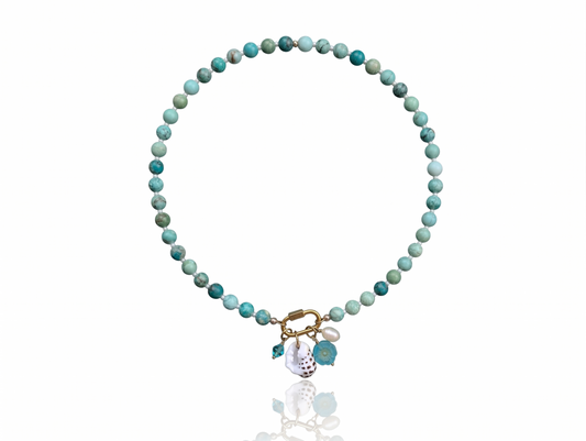 Hand-strung Peruvian turquoise gemstone necklace featuring an 18K Gold PVD oval carabiner clasp with removable charms including a turquoise Swarovski crystal, Czech glass hibiscus, Hawaiian spotted drupe shell, and freshwater pearl.