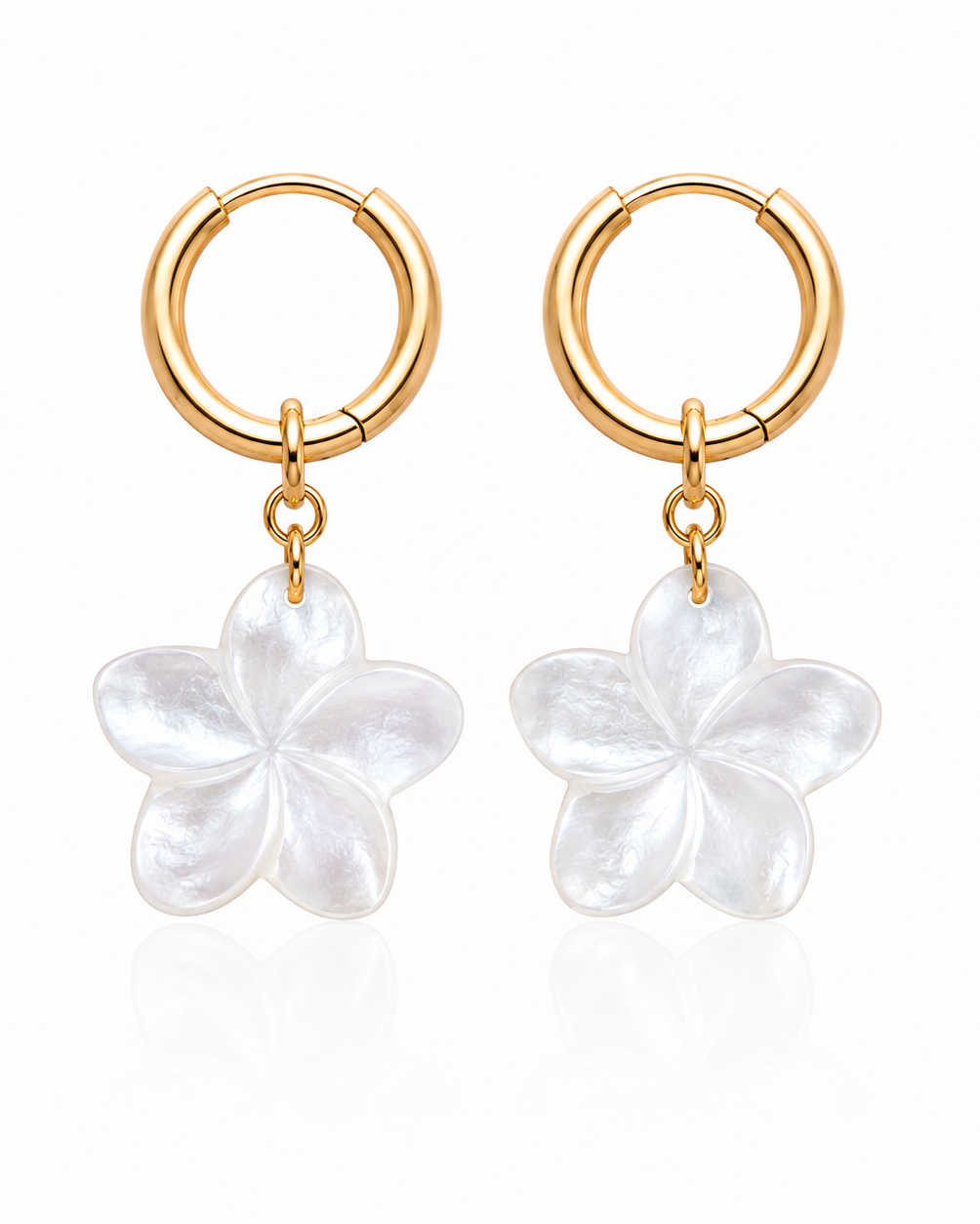 Gold hoop earrings with white flower charms on a white background